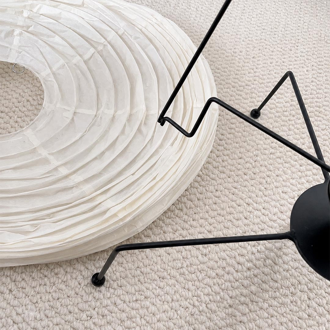 Flat-packed foldable paper shade and black metal wire components of the Washi Paper VB-13T Lamp by Stuber Lighting.